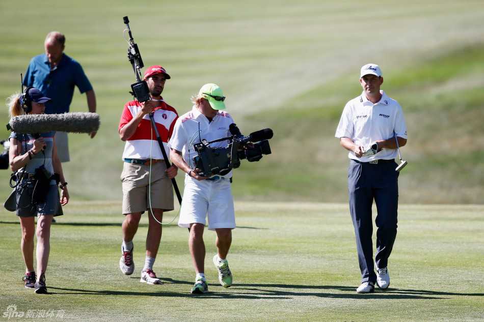 同组球员在18洞果岭边握手，结束了一场漫长的比赛。他们微微弯腰，专注地握手交流，背景是广阔的球场与夕阳的余晖。