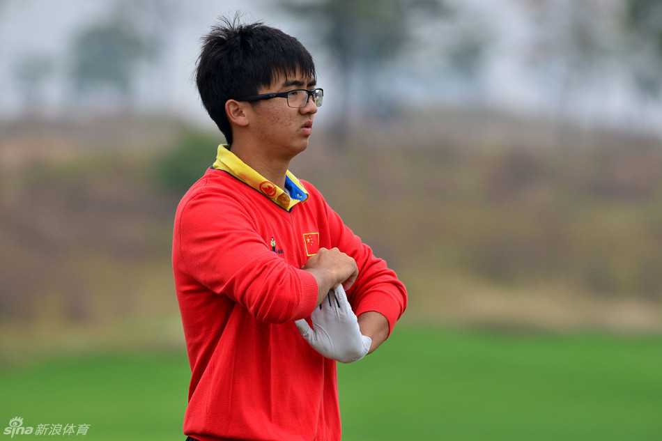 窦泽成在寒冷天气中活动手指，为精准推杆做准备，神情专注而沉稳。