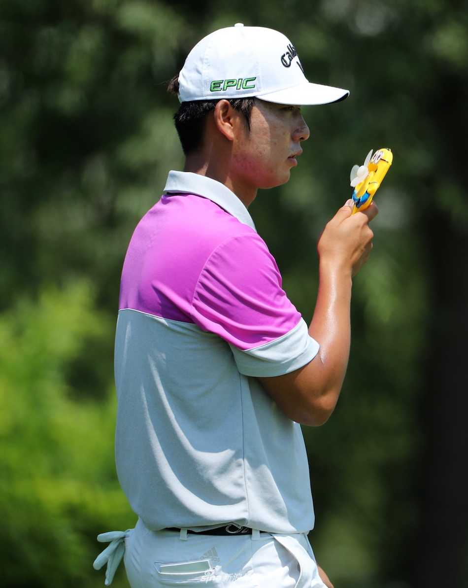 韩国选手赵乐炫在闷热的赛场边手持迷你小风扇吹风，专注的神情中透着一丝对凉爽的渴望。