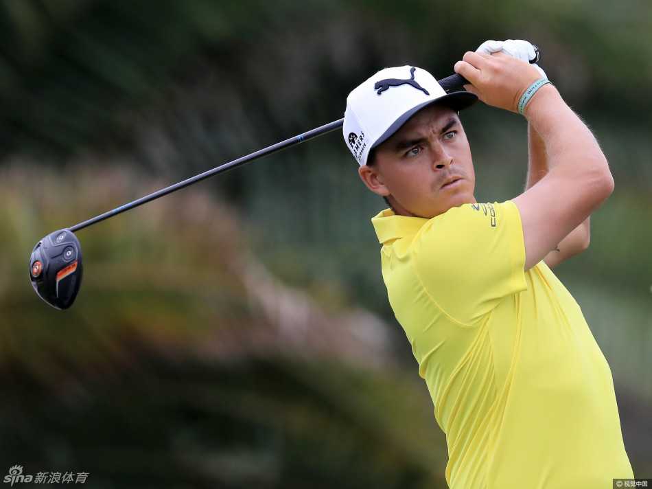 卫冕冠军亚当·斯科特在练习果岭上凝神推杆，表情专注，阳光在他的球帽上投下阴影，冠军的沉稳气质显露无遗。