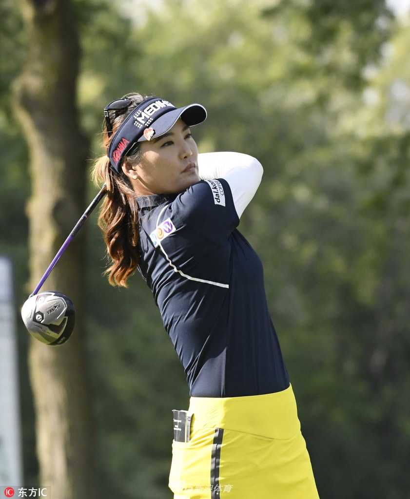 布鲁克·亨德森在长草中凝视球路，阳光勾勒出她充满力量感的挥杆预备姿态。