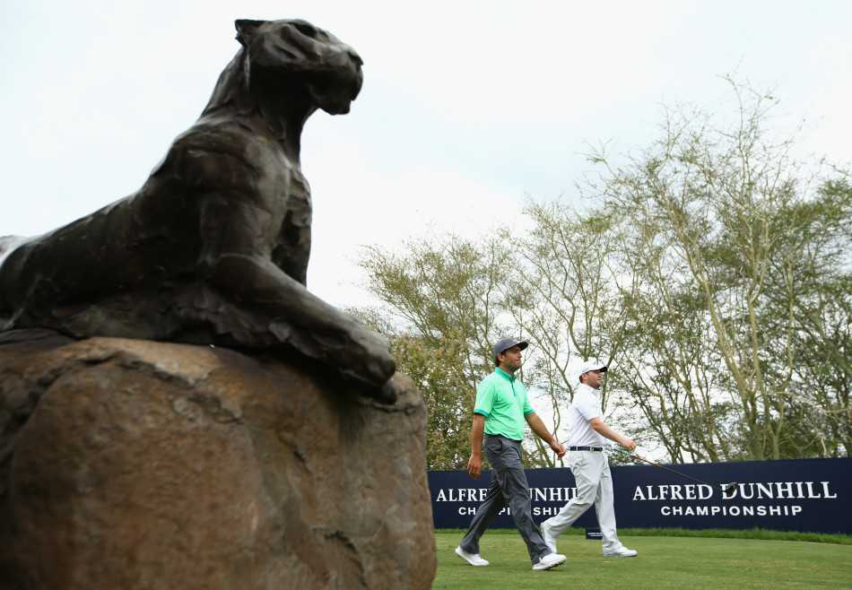 布兰登·格雷斯专注俯身，在落日余晖中观察果岭线，身旁是意大利对手莫里纳利，背景是非洲金色的荒野。