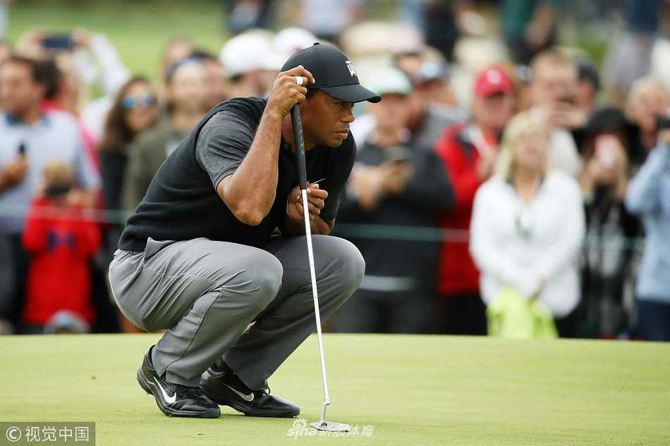 伍兹完成一记完美的收杆，身体平衡而舒展，背景是绿意盎然的球场与专注的观众