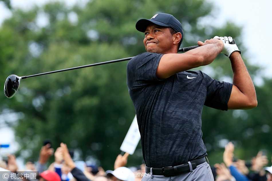 老虎伍兹在球道上凝视远方，侧影如雕塑般坚毅，阳光洒在他红色的战袍上