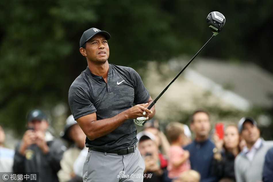 比赛结束，伍兹在记分卡上签名，神情专注，身旁观众举起手机记录这一刻