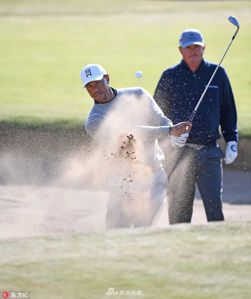 伍兹在练习轮中与球童轻松交流，两人面带笑容，展现出一派胸有成竹、自信满满的备战氛围。