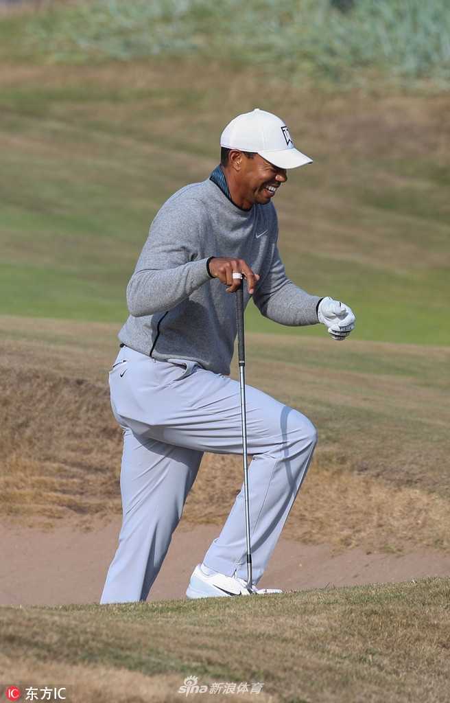 伍兹在果岭边缘进行细致的切杆练习，他单膝跪地仔细观察球的线路，展现出对短杆技术精益求精的态度。