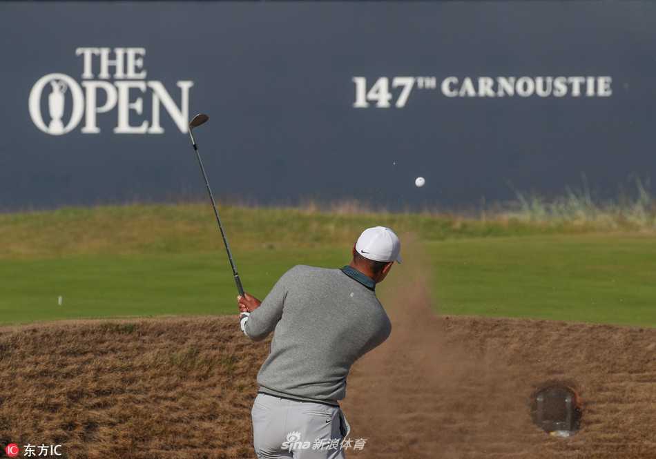 完成练习的伍兹背着球包行走在黄昏的球场上，身影被斜阳拉长，显得坚定而孤独，迈向未知的正赛挑战。