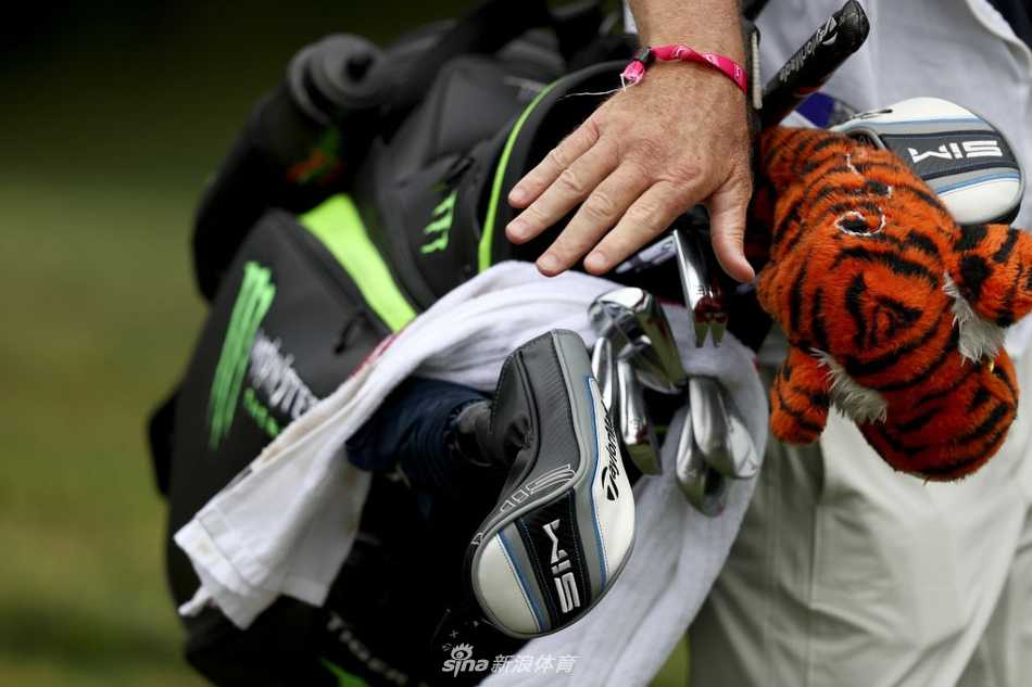 夕阳下伍兹完成比赛后离开果岭，长长的身影与金色阳光构成一幅充满故事感的画面，寓意着一段征程的暂时结束与新征程的开始。