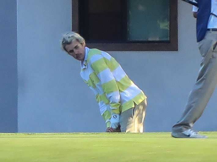 比伯在果岭边进行短杆切球练习，动作细腻专注，神情认真。