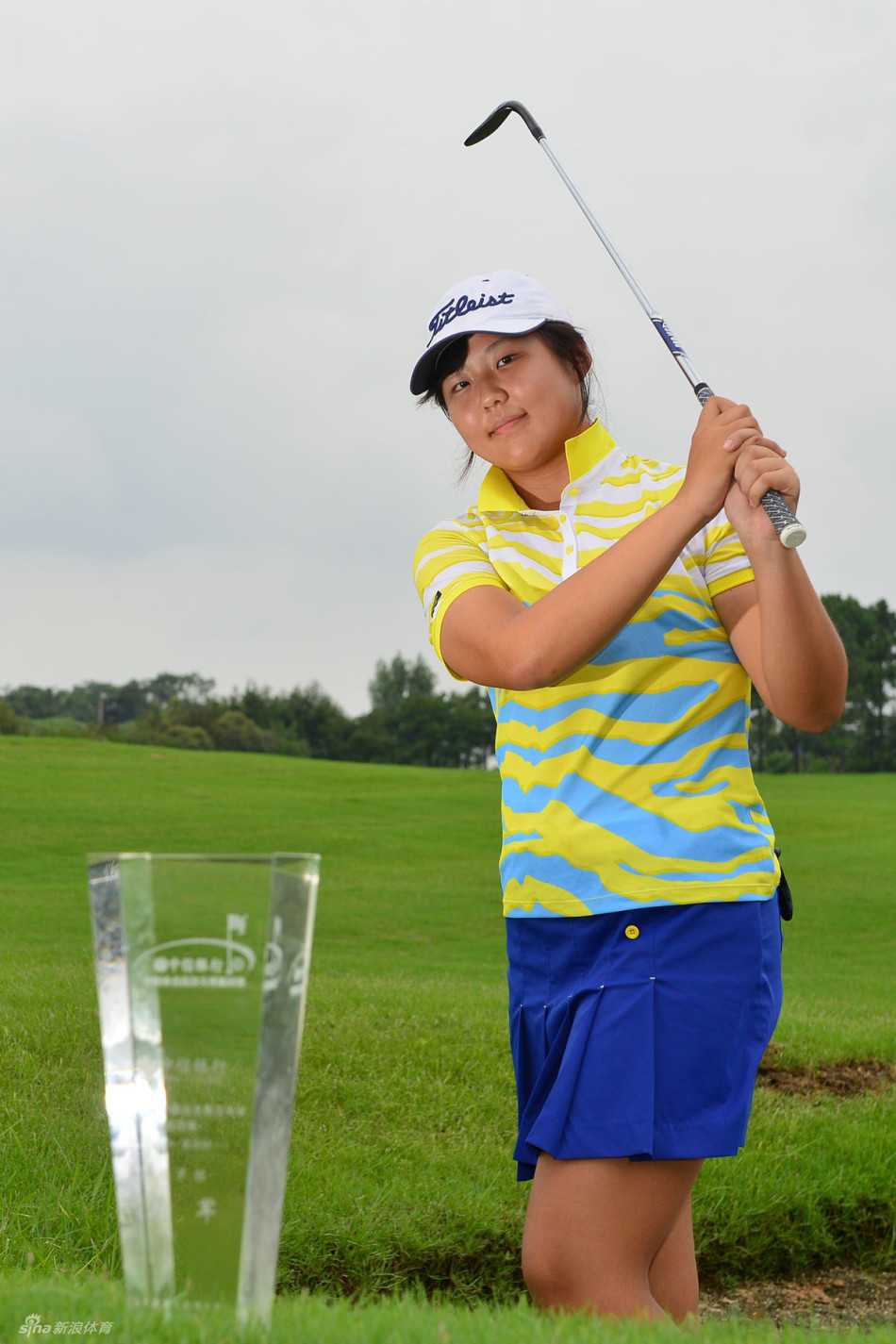 钟成恩在开球台上优雅完成上杆，背景是开阔的球场，画面充满动感与希望。