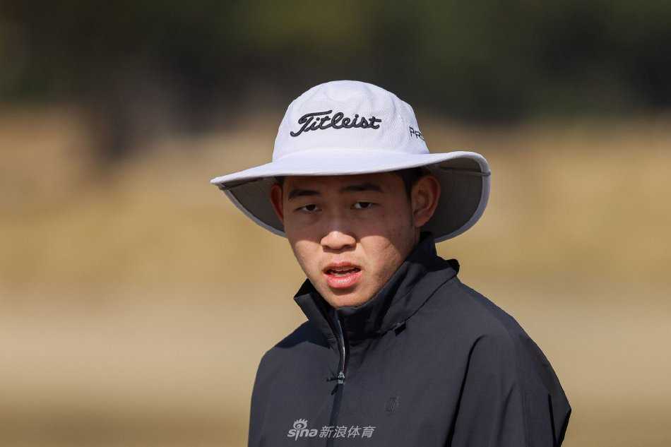 比赛间隙，球员与教练低头密商，手持记分卡分析战术，背景是辽阔的球场与蔚蓝天空。