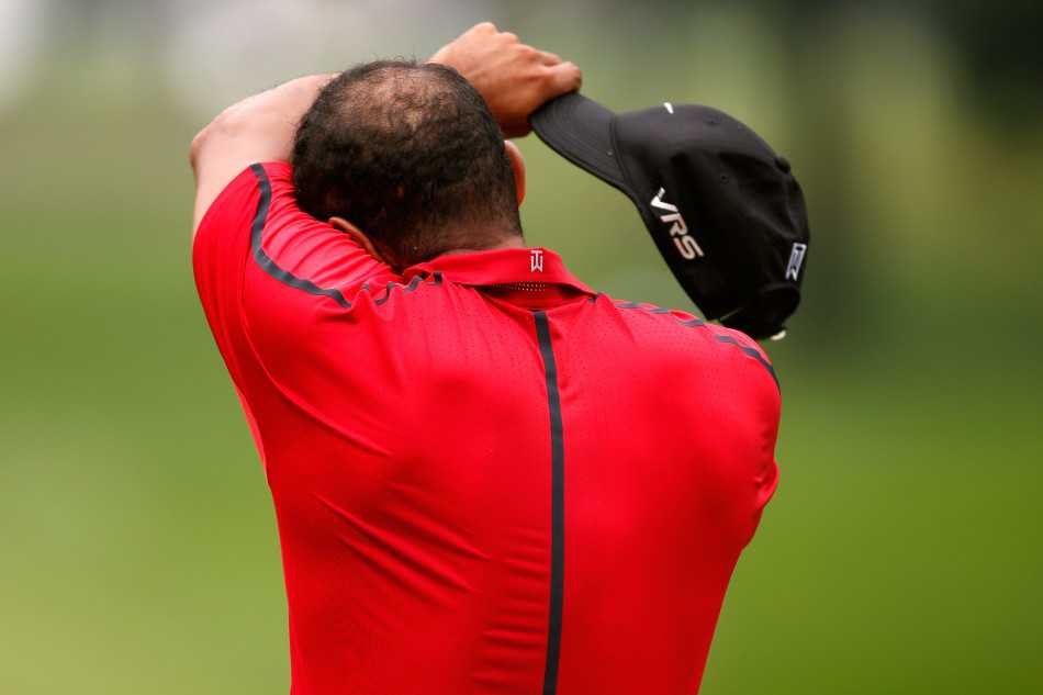 伍兹紧锁眉头擦拭额角汗水，目光低垂，疲惫与不适已爬上这位昔日王者的脸庞