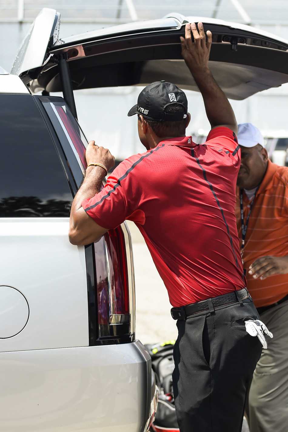 伍兹在沙坑中单腿深蹲支撑救球，表情专注而紧绷，身体承受着巨大压力