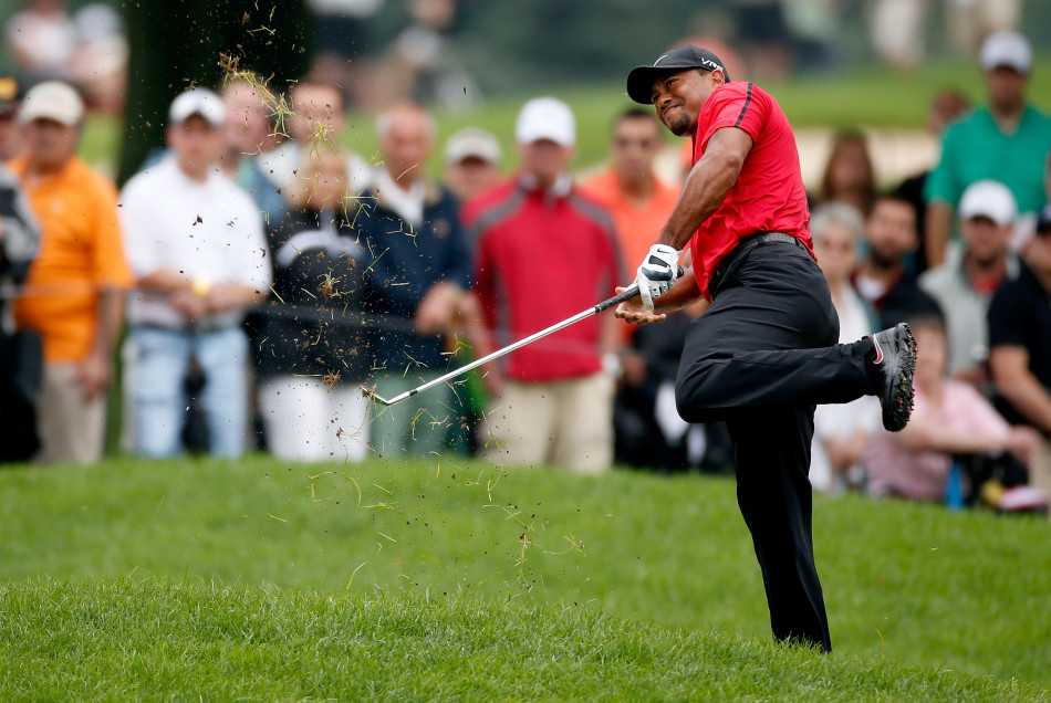 伍兹独自坐在球车后座驶离赛场，侧影落寞，仿佛一位告别战场的伤兵