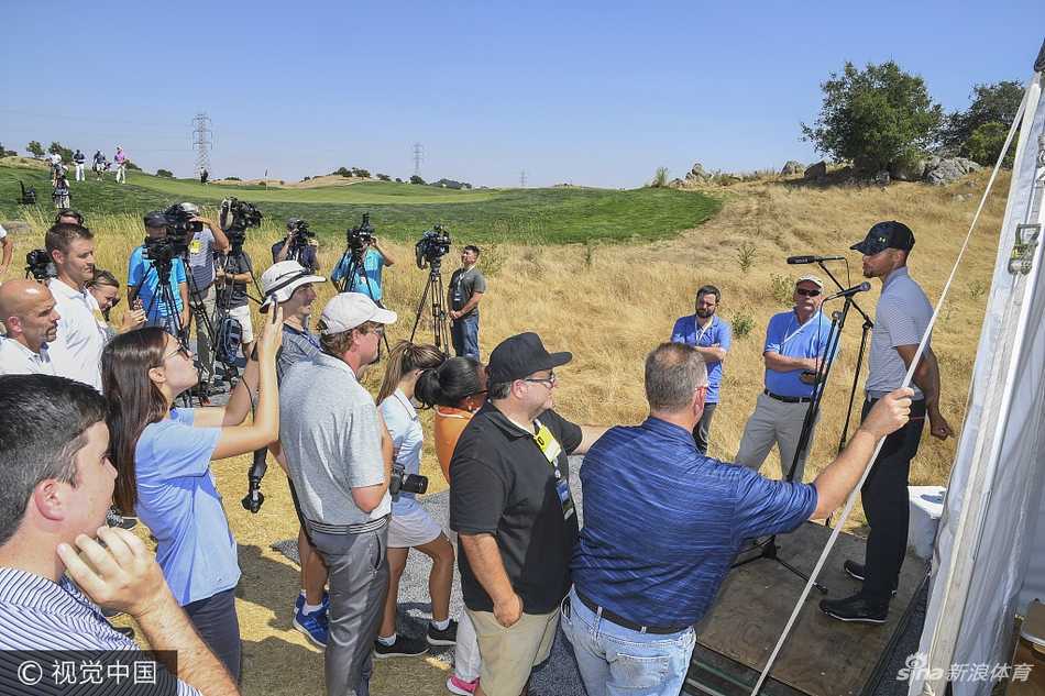 库里背着自己的高尔夫球包行走在赛道上，表情轻松笑容灿烂