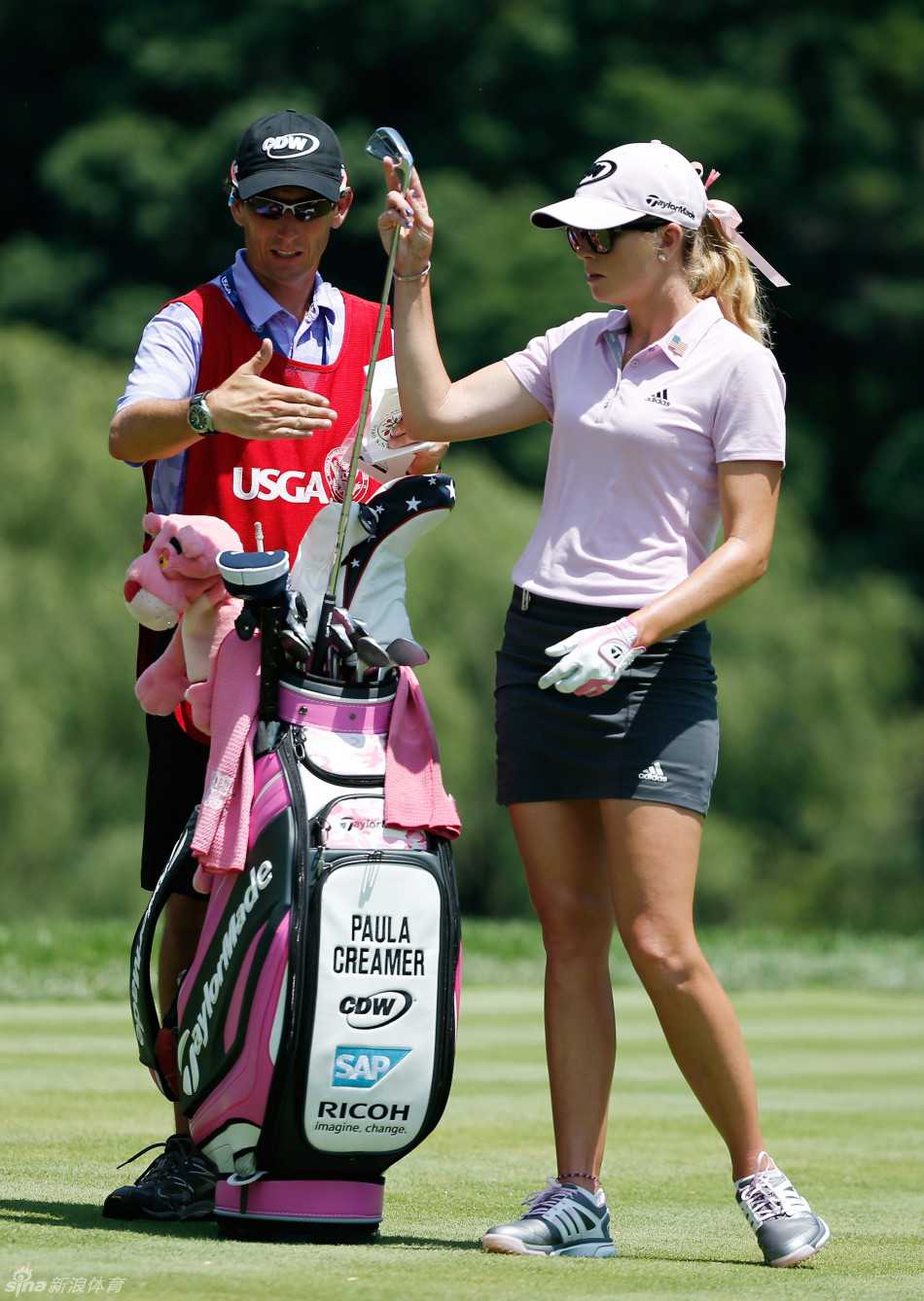 粉红意志与荣耀果岭:美国女子公开赛上的巾帼群英 克里默在果岭边仔细观察线路,与球童低声讨论,听取关键建议。