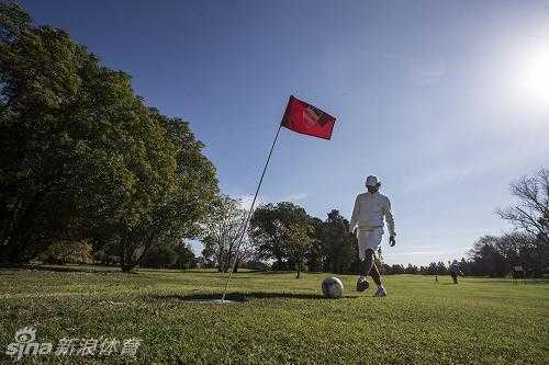 绿茵场上的智慧角逐:足球高尔夫融合运动的魅力 一名球员在果岭边小心翼翼地用脚内侧轻推足球,让球沿着草皮缓缓滚向洞杯,展现了足球高尔夫中对细腻脚法的极致要求。