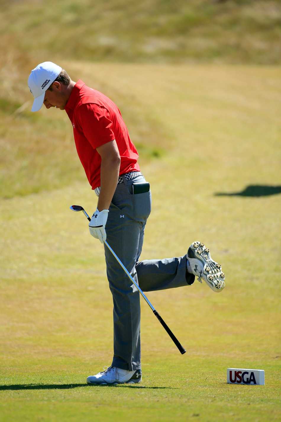 斯皮思在长草区半蹲，身体重心倾向一侧，如同金鸡独立般观察远处果岭的起伏地形。