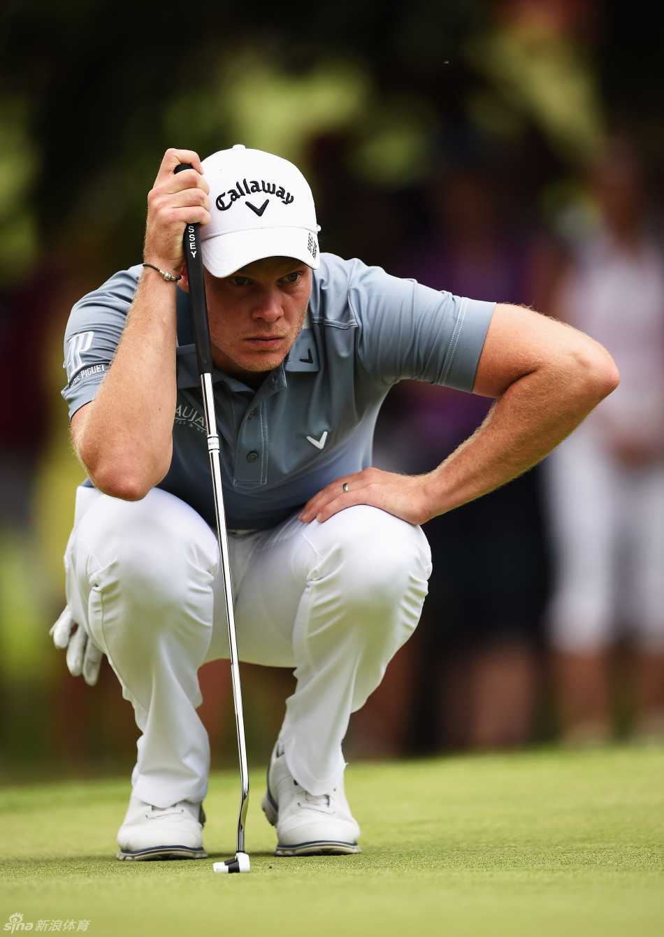 绿茵之上的全球交响:高尔夫世界的传奇与瞬间 著名球星丹尼·威利特在果岭上俯身细致察看推击线路,计算着每一丝草纹与坡度对小白球的影响。