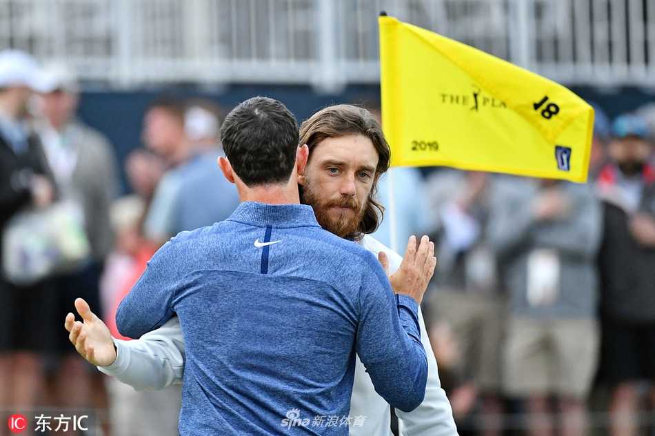 英格兰名将汤米·弗利特伍德与北爱尔兰巨星罗里·麦克罗伊在赛道上并肩同行，面带微笑，仿佛正在分享一个轻松的故事。