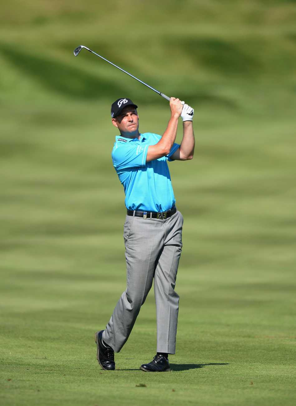 绿茵之上的平衡艺术高尔夫挥杆的流畅美学 南非名将乌修仁在练习场专注地进行击球准备,目光如炬地凝视前方球道,展现了职业球员的精准与沉着。