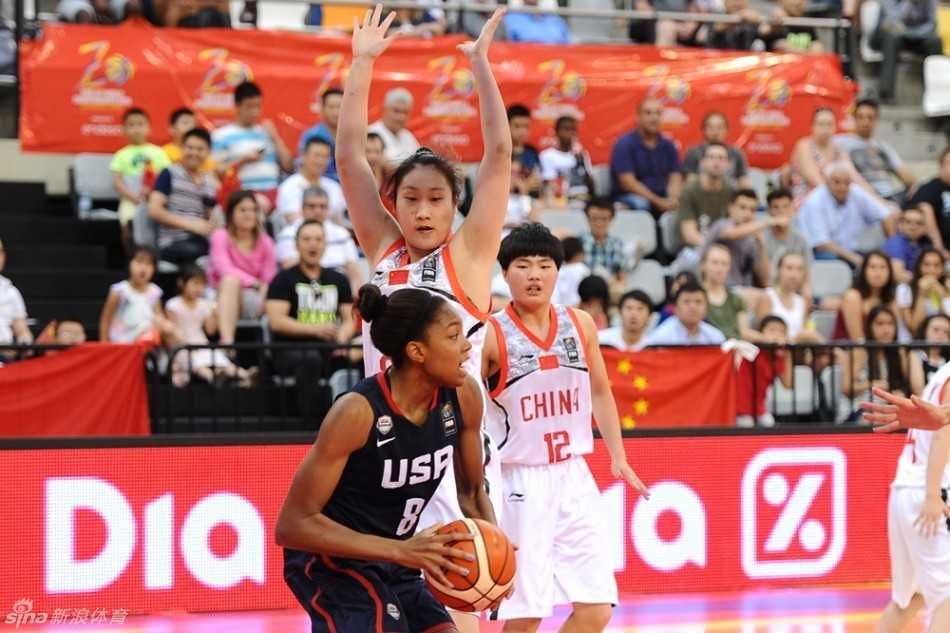 U17女篮世青赛中国小花绽放赛场不畏强手拼得第四名 一名中国队员在对方严密的防守下高高跃起,双手持球举过头顶,正准备完成一次关键的投篮。防守球员的手已经封到了脸上,但她的出手依然坚决果断。