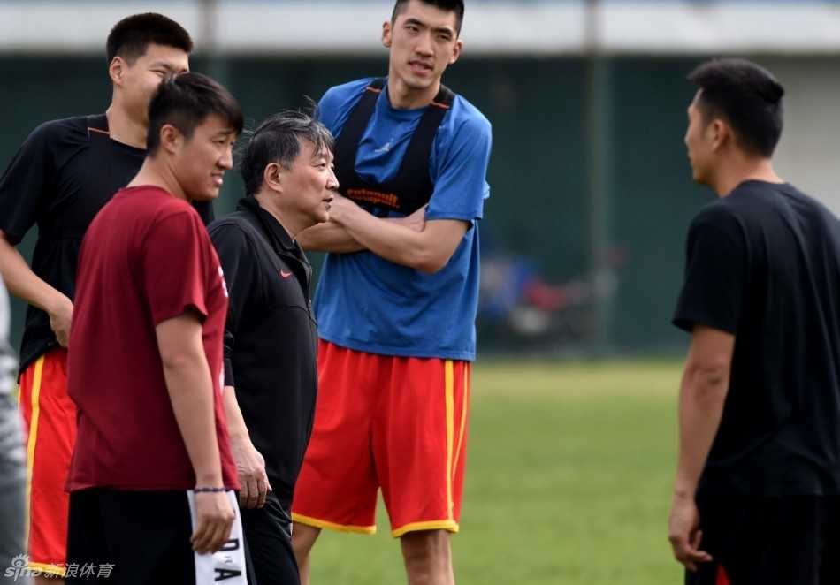 可兰白克坐在地上专注地进行腿部拉伸，李慕豪在一旁压腿，脸上带着轻松的笑意，气氛融洽