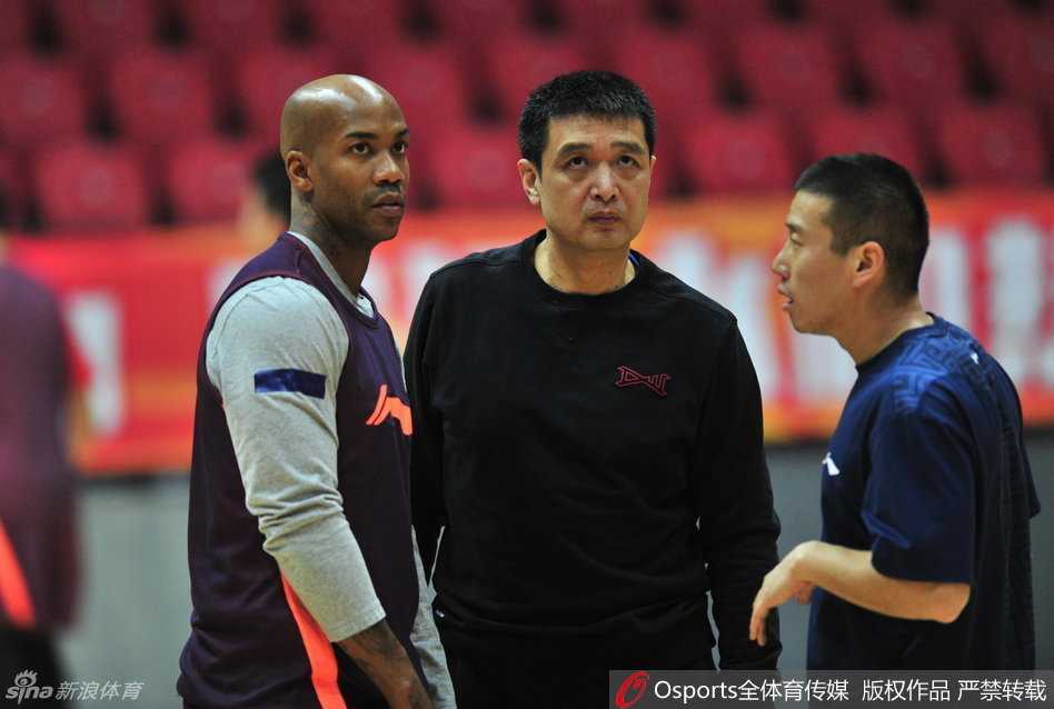 主教练闵鹿蕾神情专注地拿着战术板，向球员比划着战术跑位，眼神中透露出对胜利的渴望与坚定。