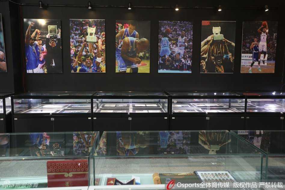 在陈列着三座CBA总冠军奖杯的展柜前，马布里深情凝望。这三座金灿灿的奖杯，不仅是他个人职业生涯的巅峰，更是他与首钢兄弟们并肩作战、征服联盟的最好证明。