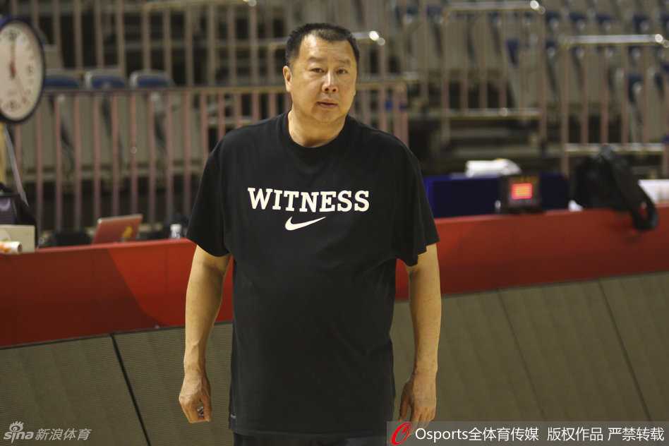 助教单涛神情专注地站在场边，双手比划着战术动作，正在对常林和陶汉林等内线球员进行细致的防守脚步指导，展现出职业教练的严谨。