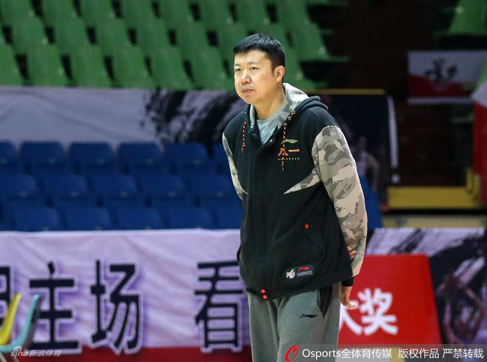 新任教练王治郅在场边神情专注地观看着队员们的训练，双臂环抱，眼神中透露出作为主帅的严肃与责任感。