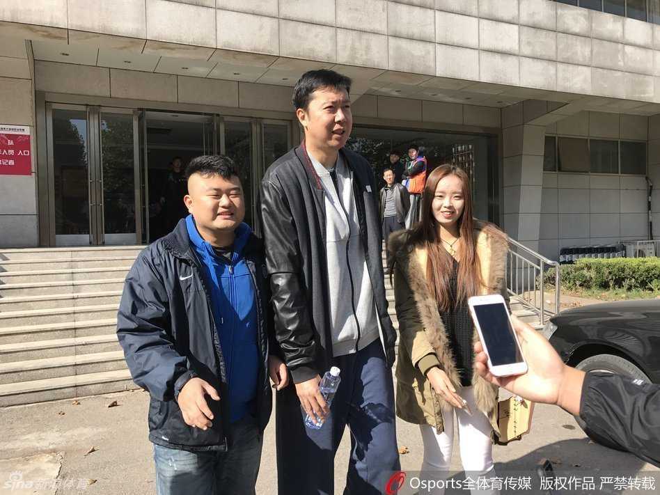 王治郅手拿战术笔记本，在训练场边专注地指导年轻球员，神情认真而投入，从球员到教练的转型在他身上显得自然而沉稳。