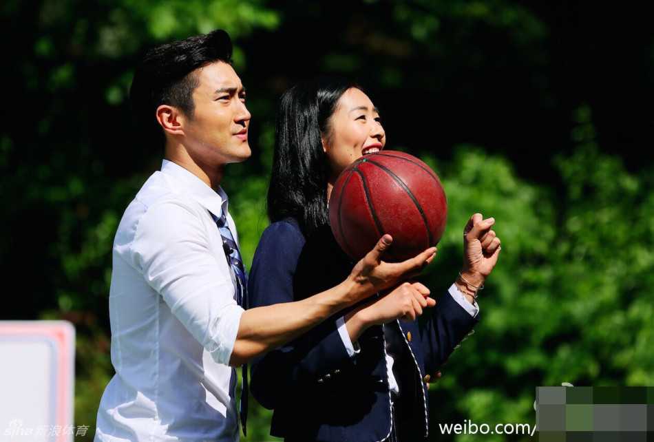 崔始源在篮下准备投篮，不远处的刘雯全神贯注地看着他的动作，脸上带着期待又俏皮的表情，仿佛在为他默默加油