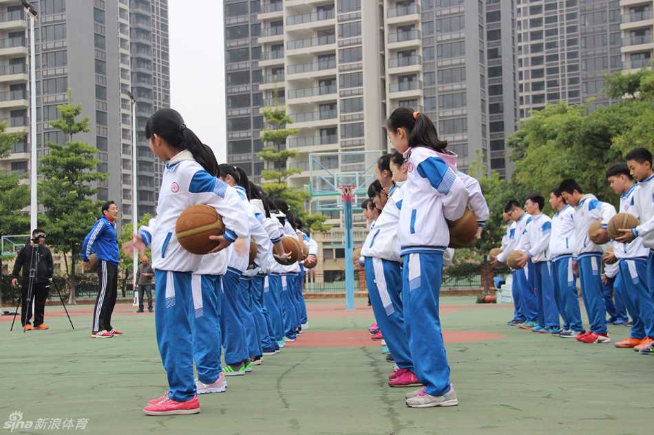 小队员在场上进行动作示范，李群站在身侧认真观察准备随时纠正细节