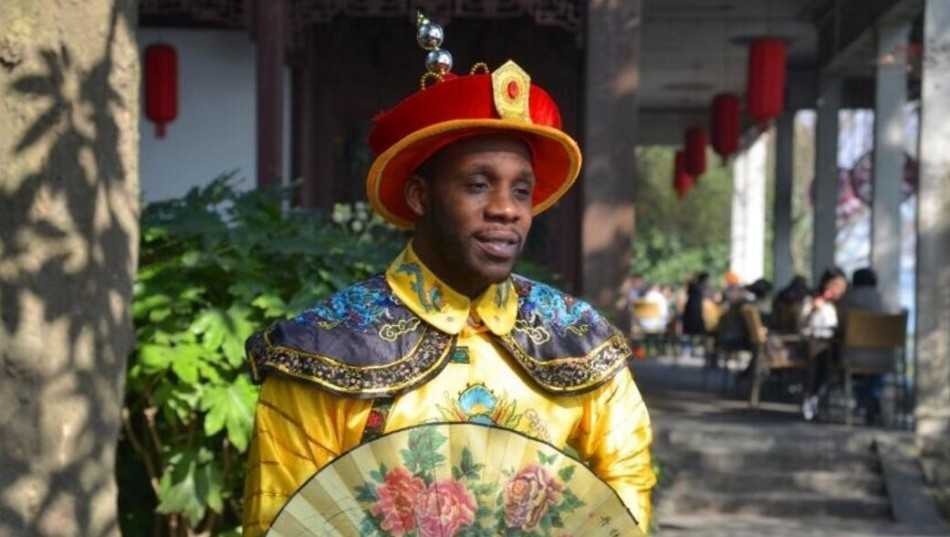 哈德森身穿金色龙袍气宇轩昂，怀抱小女儿尽显铁汉柔情，身旁的大女儿乖巧可爱，一家人在影楼的中式布景前留下珍贵合影