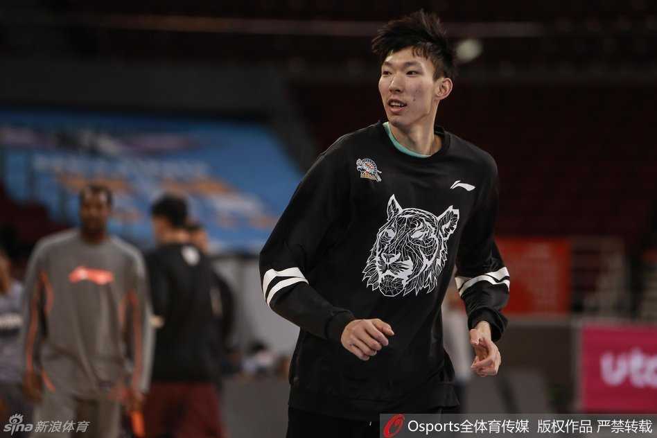 主教练李秋平双手叉腰站在场边，神情严肃地注视着球员们的训练，嘴里不时喊着战术指令