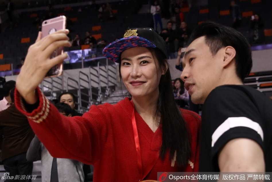 许诺在看台上低头玩弄手机，神情专注，时而抬头观望赛场，修长的手指在手机屏幕上滑动，显得十分惬意