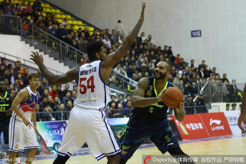 前NBA名将布泽尔身穿广东队服，面对天津泰勒的贴身长臂干扰，高高跃起准备施展他招牌式的直臂跳投，眼神专注而坚定。