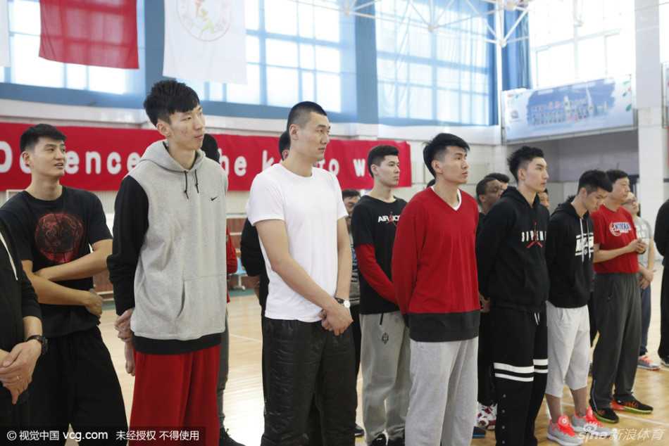 寒冬里的暖流:忆二零一六年春城慰问新疆男女篮将士 镜头拉近,一位新疆男篮的队员手中紧握着红色的慰问红包,背景是悬挂着巨大篮筐的训练墙,他的眼神中流露出超越年龄的沉稳与坚定