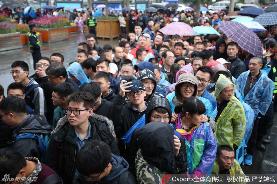 售票窗口前人头攒动，一位刚抢到球票的球迷兴奋地将手中的红色票根高高举起，脸上洋溢着满足而灿烂的笑容，仿佛握住了通往总决赛巅峰之战的珍贵入场券。