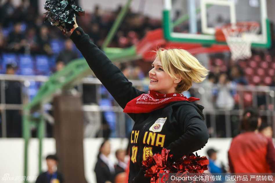 一位啦啦队员手持蓝色花球，自信地面对镜头，洁白的牙齿和弯弯的笑眼展现出她迷人的魅力，仿佛阳光洒满赛场。