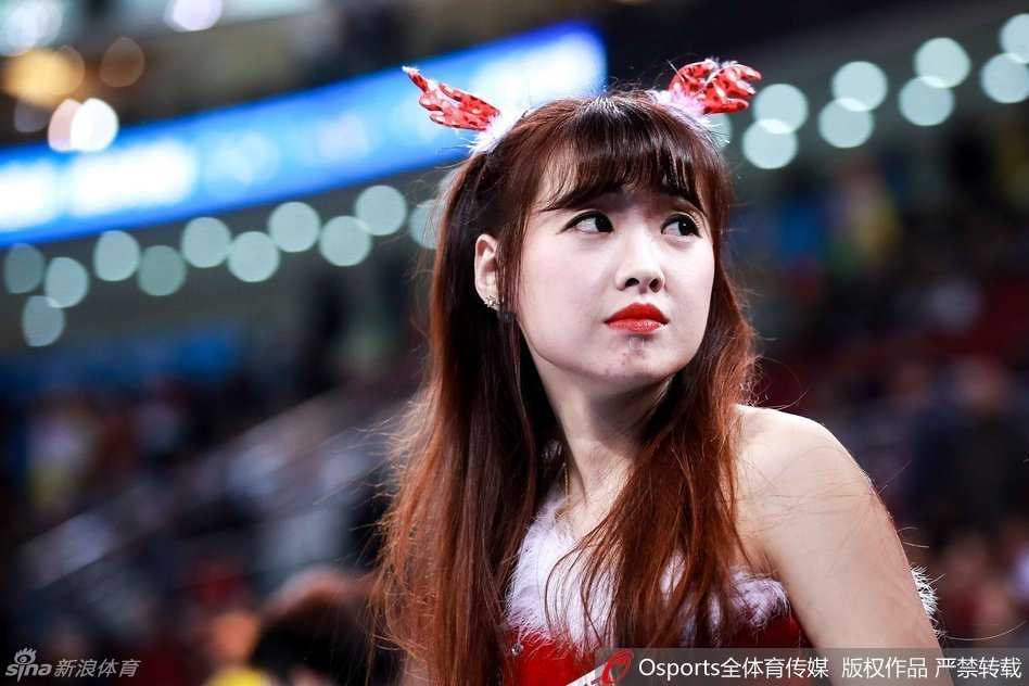 两位拉拉队员在场地边亲密互动，她们头上都戴着可爱的驯鹿角发饰，脸上洋溢着灿烂的笑容，圣诞气氛十足。