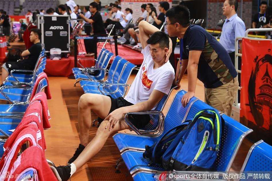 镜头拉近，李慕豪低垂着头，左腿上缠着厚厚的绷带，脚踝处隐约可见冰敷的痕迹，肿胀让他甚至无法穿着鞋子。