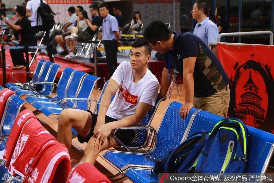 坐在替补席上的李慕豪神情落寞，眼神中充满了无法上场的无奈与对赛场的渴望，身旁的队友们正在激烈热身。