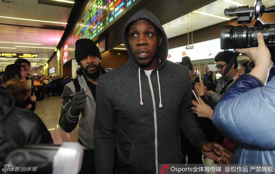 无论成败与辽同在:那年春天沈阳机场的温情接机 画面中,留着标志性莫西干发型的外援哈德森神情专注,正低头为热情的球迷在纪念品上签名,一旁的兰多夫也伸手接过球迷的物品,两人身边是无数双充满期待的眼睛和伸出的手臂。