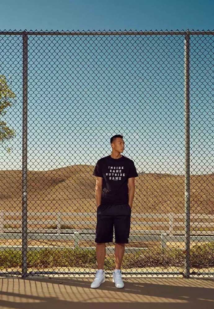 易建联置身于一片明亮的自然光中，他放松地倚靠在墙边，露出一抹温暖而含蓄的微笑，仿佛在与老友叙旧，传递出满满的亲和力。