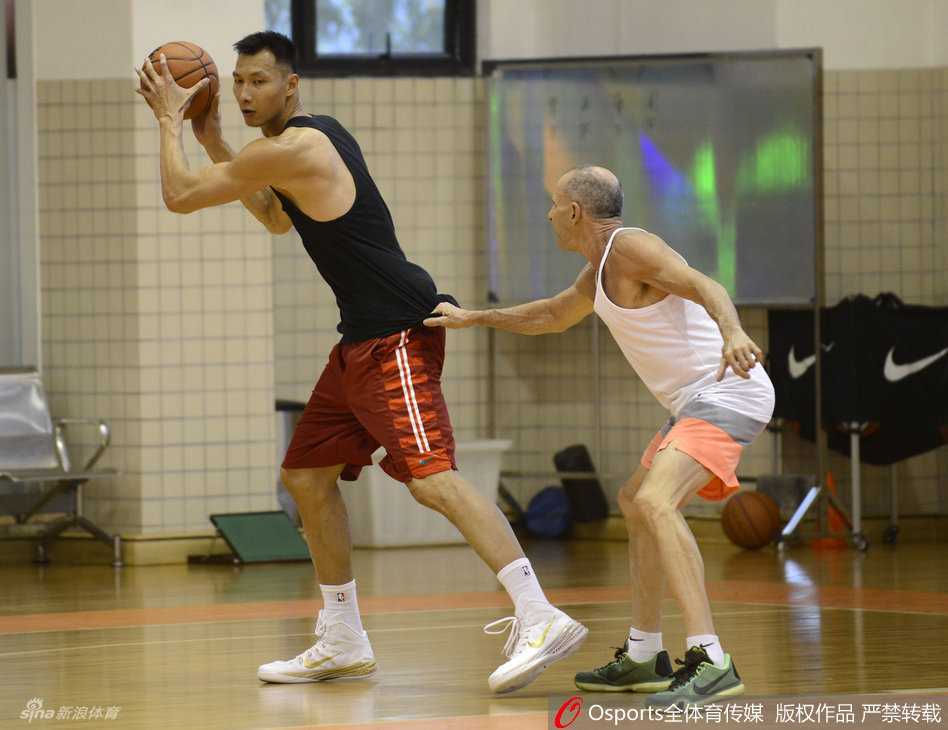 易建联在训练馆中全神贯注，双手稳稳持球，眼神犀利地审视着篮筐，仿佛即将面对的不仅是训练，而是内线强悍的对手。