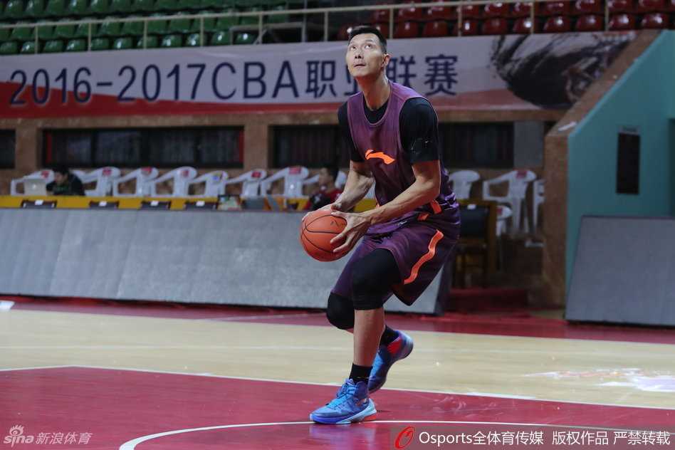 易建联在篮筐侧面进行跳投热身，眼神专注，肌肉线条在训练服下若隐若现。