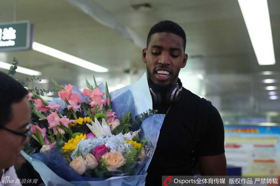 走出机场通道的汤普森面对接机人群，眼神中带着旅途的疲惫与对新征程的渴望，身后巨大的行李箱装满了他在NBA八年的回忆与荣誉。